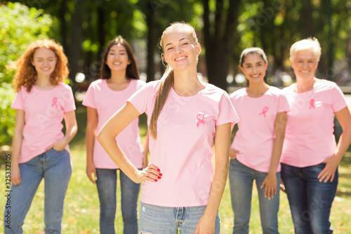 Girl With Breast Cancer Ribbon Standing With Volunteers Group Outdoor