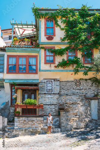 Kavala, Greece, 15/07/2019: Streets of ancient Greek city by the sea and its unique architecture. Girl standing in front of the building.