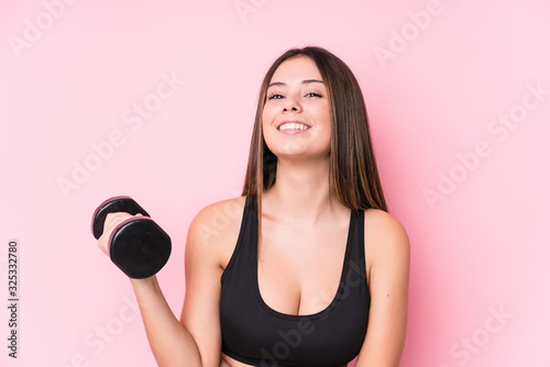 Young caucasian sporty woman holding a dumbbell