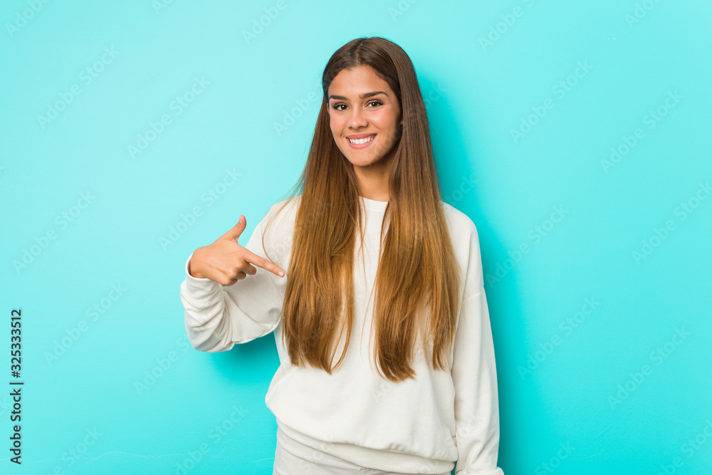 Fototapeta premium Young slim woman person pointing by hand to a shirt copy space, proud and confident