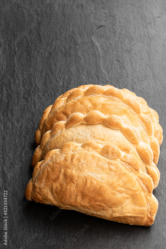 Homemade flaky pasty with mince meat filling on black stone background Homemade flaky pasty with mince meat filling on black stone background