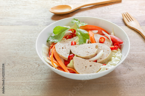 close up of spicy vietnamese pork sausage salad in a ceramic bowl on wooden table. delicious asian style food menu.