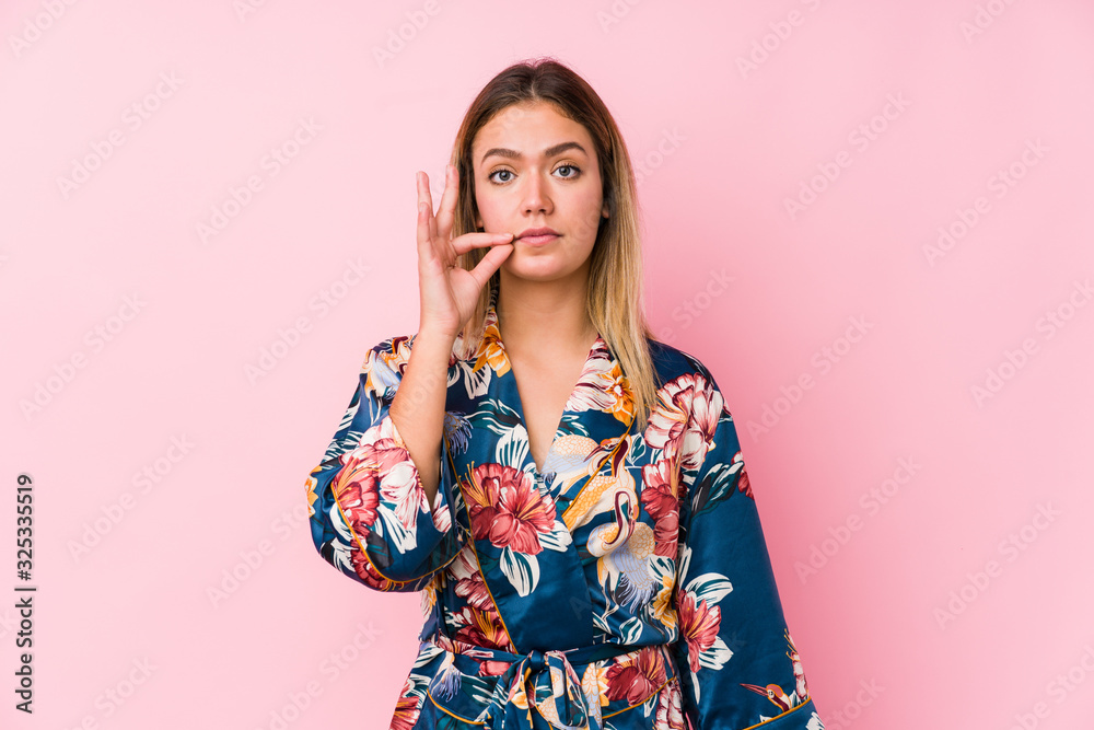 Young caucasian woman wearing pajamas with fingers on lips keeping a secret. Young caucasian woman wearing pajamas with fingers on lips keeping a secret.