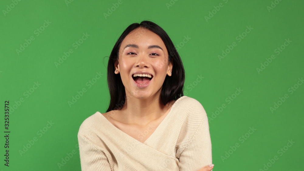 Beautiful young cheerful funny Asian girl happily smiles into the camera portrait with a natural skin tone with minimal amount of makeup on her face. A concept of a positive mood, a mood for joy, fun Beautiful young cheerful funny Asian girl happily smiles into the camera portrait with a natural skin tone with minimal amount of makeup on her face. A concept of a positive mood, a mood for joy, fun
