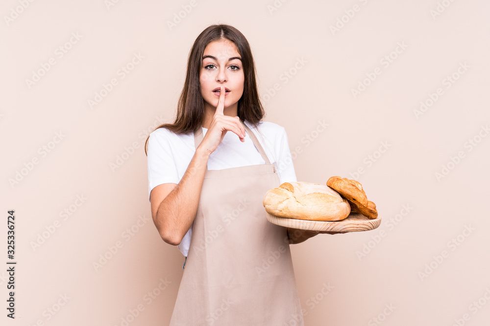 Young caucasian baker woman isolated keeping a secret or asking for silence. Young caucasian baker woman isolated keeping a secret or asking for silence.