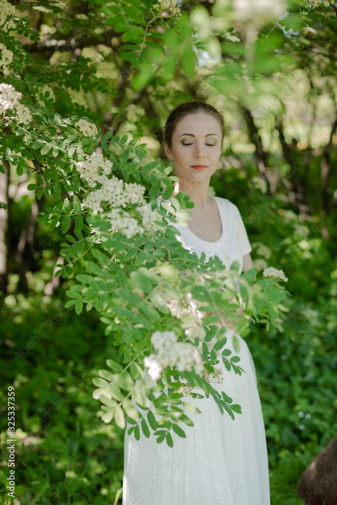 Beautiful girl is walking in the spring park near the trees in bloom. Spring season, sunny weather. Beautiful girl is walking in the spring park near the trees in bloom. Spring season, sunny weather.