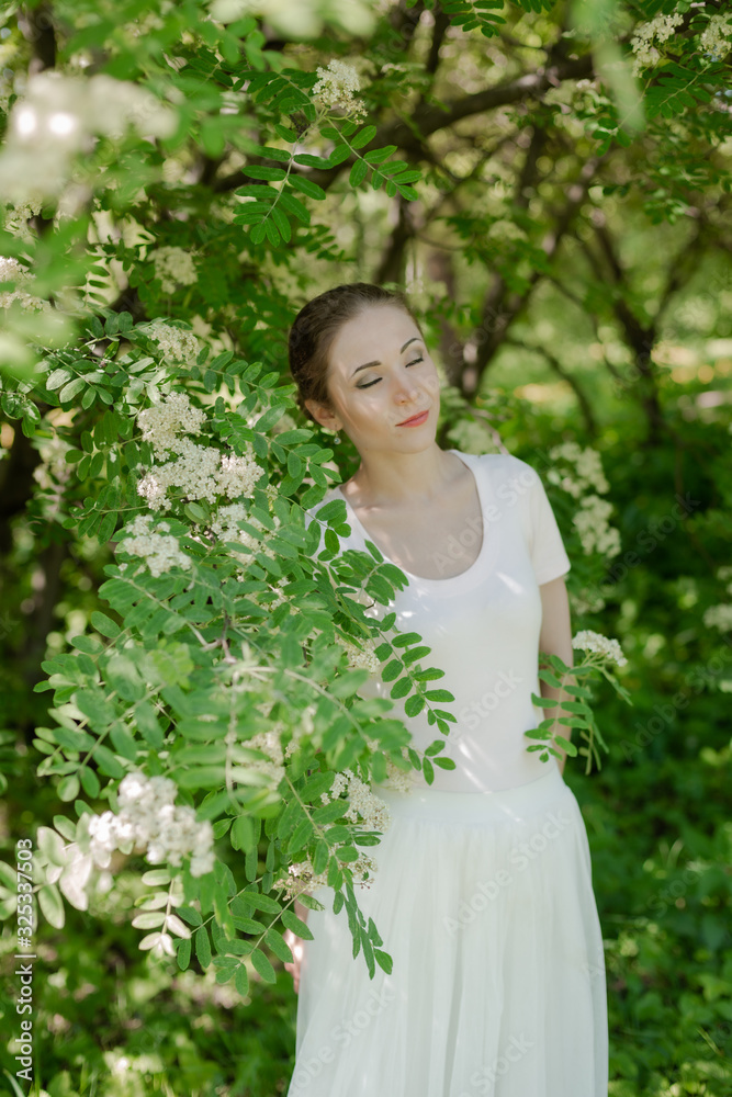 Beautiful girl is walking in the spring park near the trees in bloom. Spring season, sunny weather. Beautiful girl is walking in the spring park near the trees in bloom. Spring season, sunny weather.