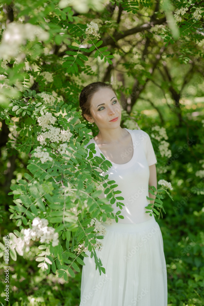 Beautiful girl is walking in the spring park near the trees in bloom. Spring season, sunny weather. Beautiful girl is walking in the spring park near the trees in bloom. Spring season, sunny weather.
