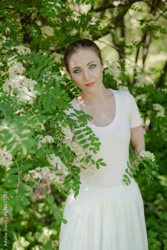Beautiful girl is walking in the spring park near the trees in bloom. Spring season, sunny weather. Beautiful girl is walking in the spring park near the trees in bloom. Spring season, sunny weather.