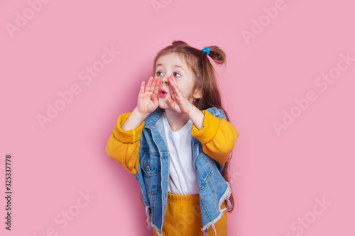 cute little girl with hands by mouth shouting on pink background