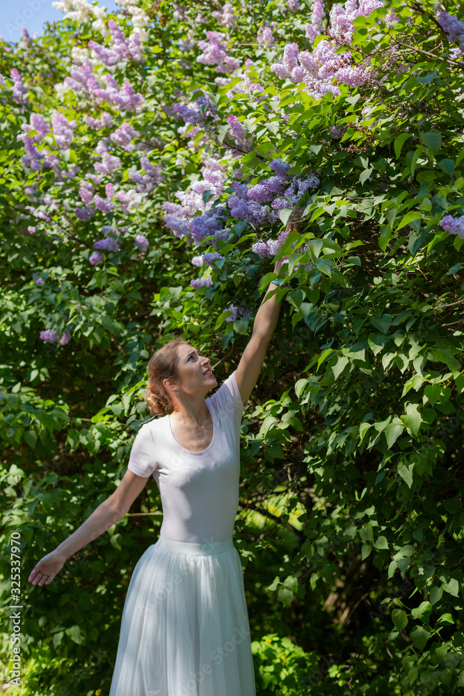 Beautiful girl is walking in the spring park near the trees in bloom. Spring season, sunny weather. Beautiful girl is walking in the spring park near the trees in bloom. Spring season, sunny weather.