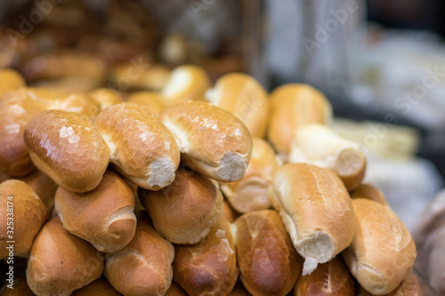 Fresh baguettes are arranged in a stack on top of each other, against a blurred background. The Market, Jerusalem.