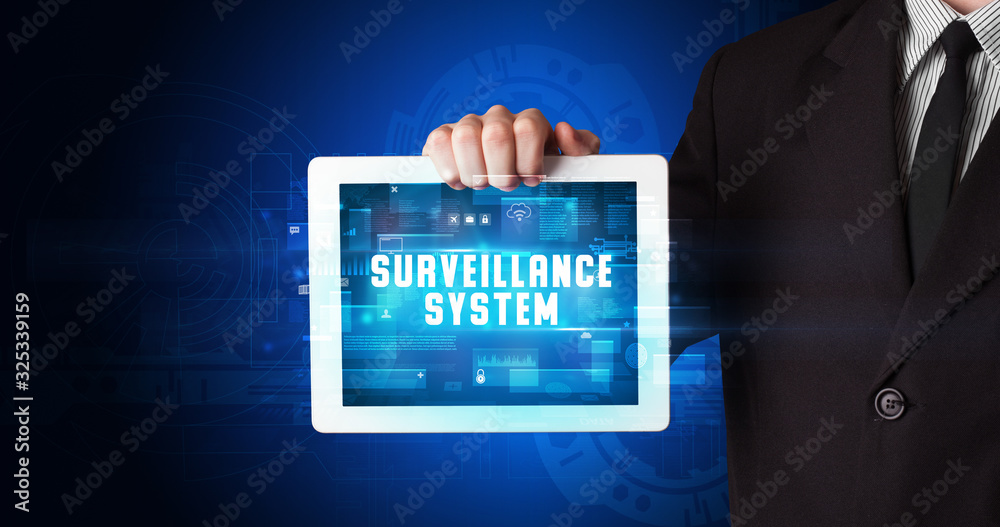 Young business person working on tablet and shows the digital sign: SURVEILLANCE SYSTEM Young business person working on tablet and shows the digital sign: SURVEILLANCE SYSTEM