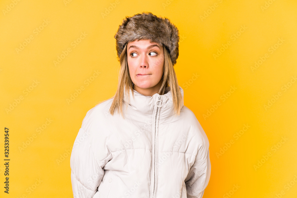 Young blonde caucasian woman wearing a winter clothes isolated confused, feels doubtful and unsure. Young blonde caucasian woman wearing a winter clothes isolated confused, feels doubtful and unsure.
