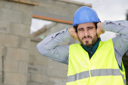 construction worker covering ears to ignore annoying loud noise photo