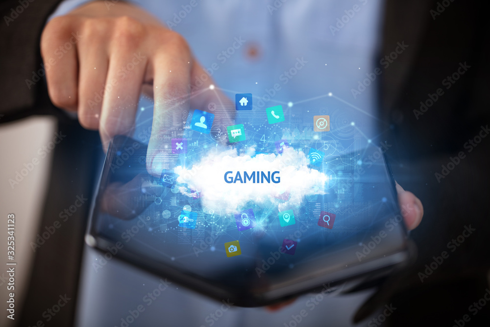 Businessman holding a foldable smartphone with GAMING inscription, technology concept Businessman holding a foldable smartphone with GAMING inscription, technology concept
