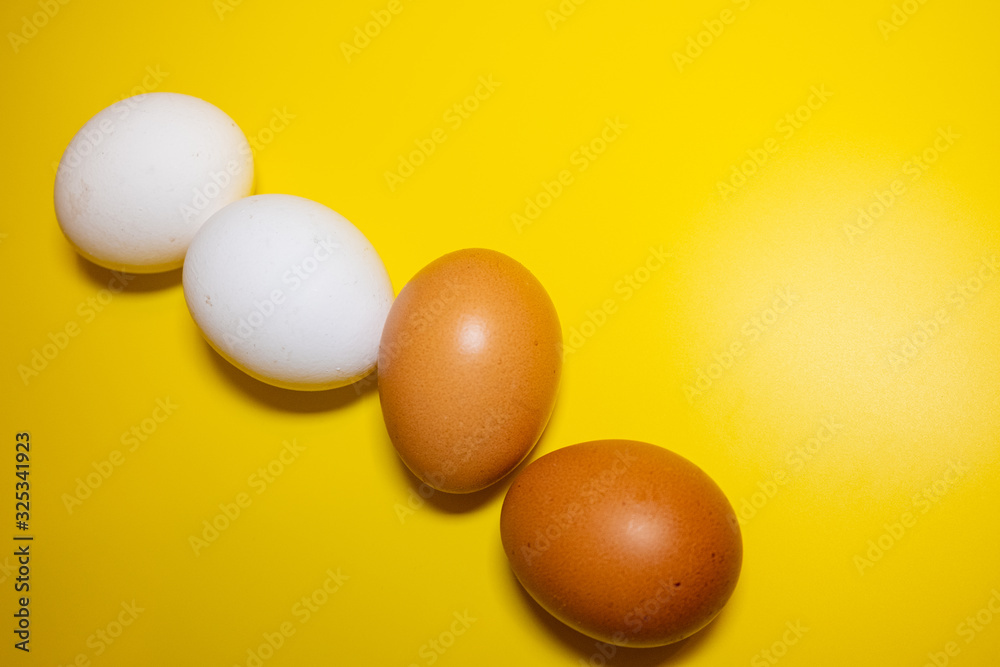 White and brown Easter eggs bright yellow background. Concept happy Easter. Minimalism concept. Top view. White and brown Easter eggs bright yellow background. Concept happy Easter. Minimalism concept. Top view.