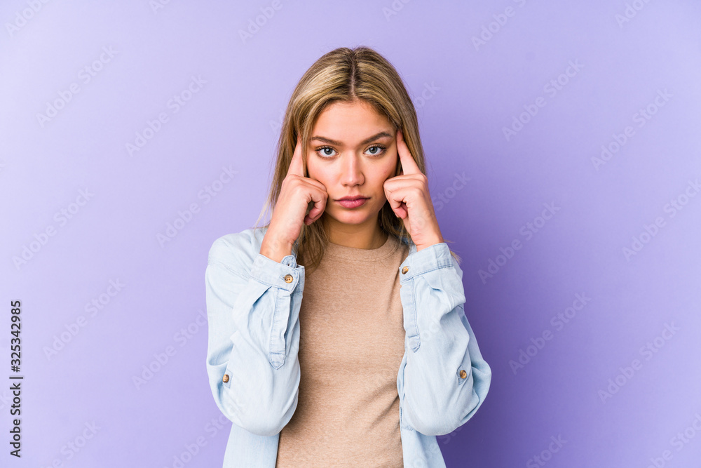 Young blonde caucasian woman isolated focused on a task, keeping forefingers pointing head. Young blonde caucasian woman isolated focused on a task, keeping forefingers pointing head.