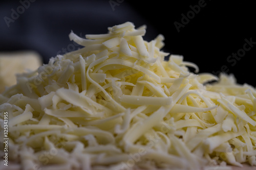 Close up of grated yellow cheese against dark background