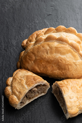 Fotografie Homemade flaky pasty with mince meat filling on black stone background