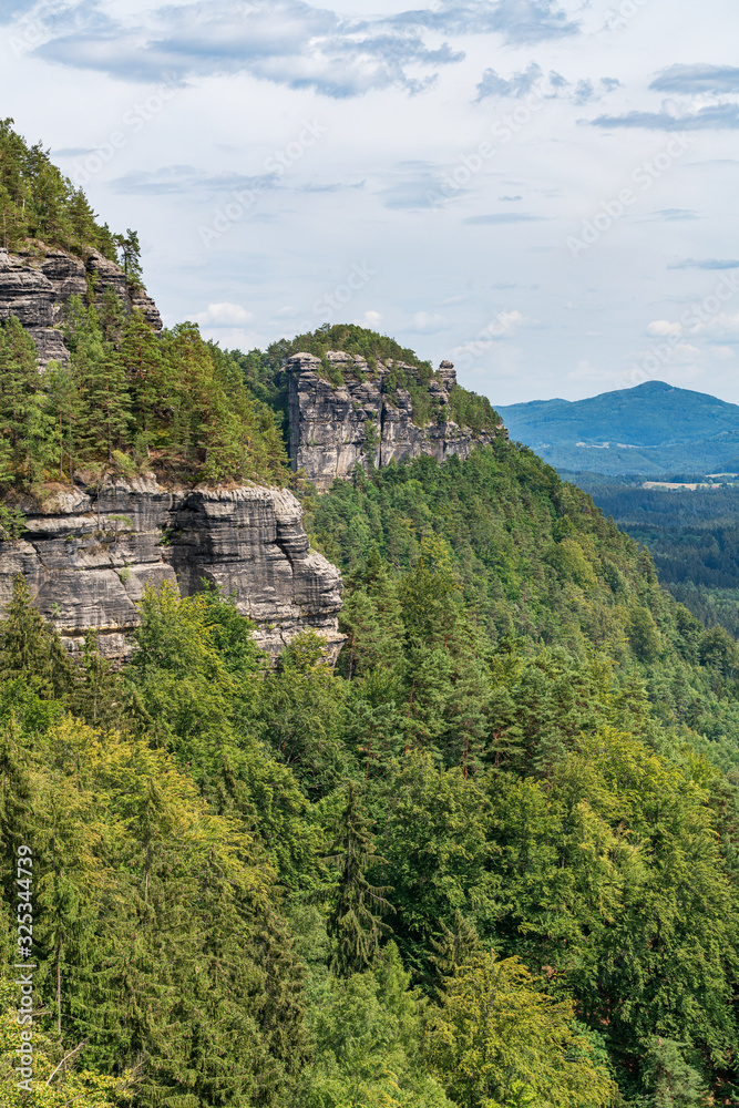Pravcicka brana in Bohemian Switzerland. Prebischtor Gate mountain view. Narrow rock, largest natural sandstone arch in Europe. Hill scenery with greenery, blue sky and sunlight, natural environment.