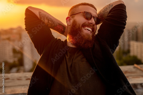 Happy hipster resting on roof in evening