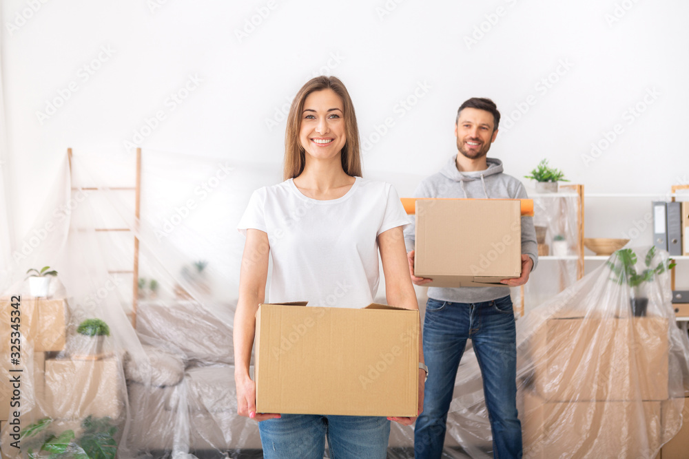 Happy young couple collecting clothes into boxes and planning repair Happy young couple collecting clothes into boxes and planning repair