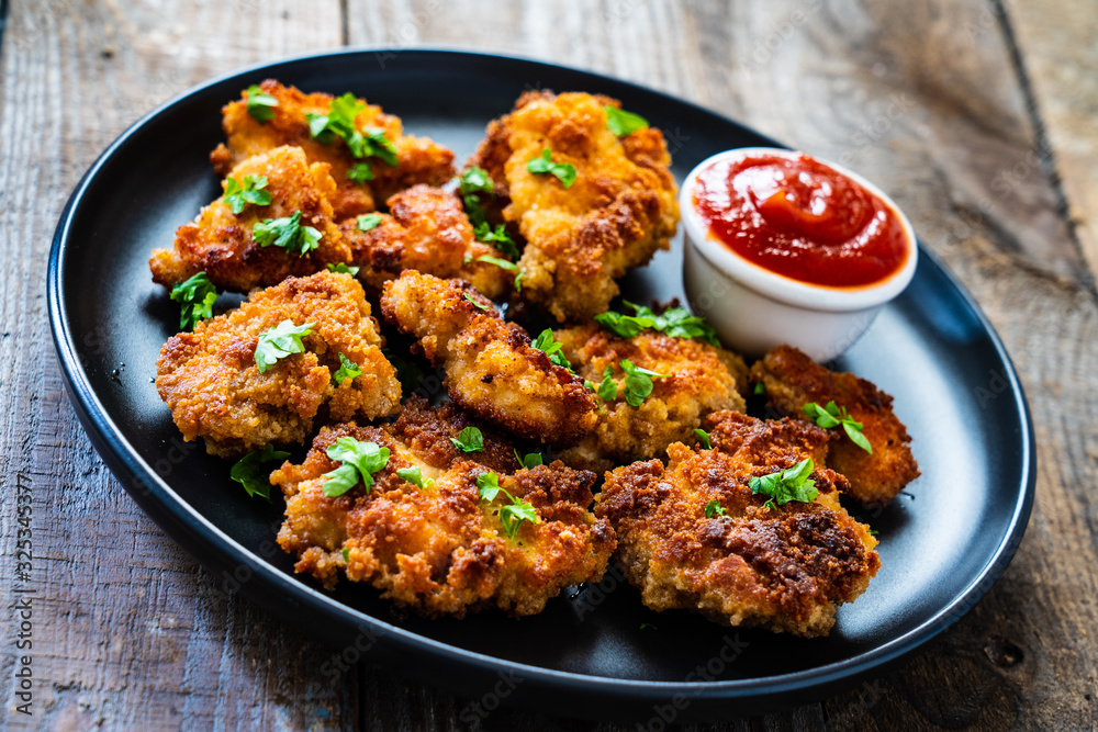 Fried chicken nuggets with ketchup on wooden table Fried chicken nuggets with ketchup on wooden table