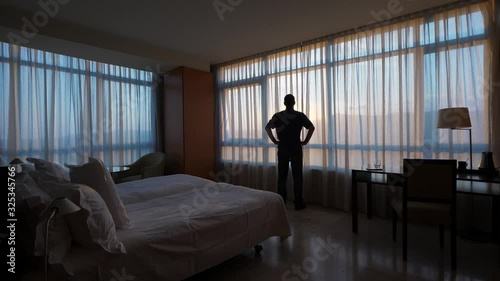 Silhouette of man standing alone against window in empty room