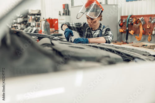 Wall Mural Young car mechanic working with locking pliers