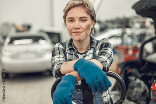 Smiling mechanic in protective gloves standing in a garage