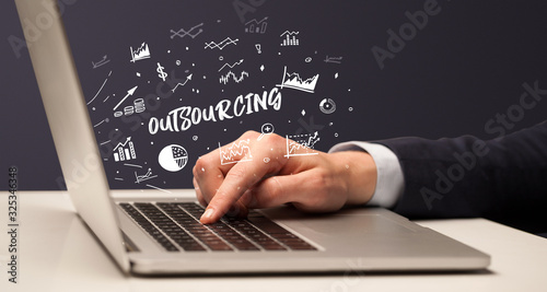 Businessman working on laptop with OUTSOURCING inscription, modern business concept photo