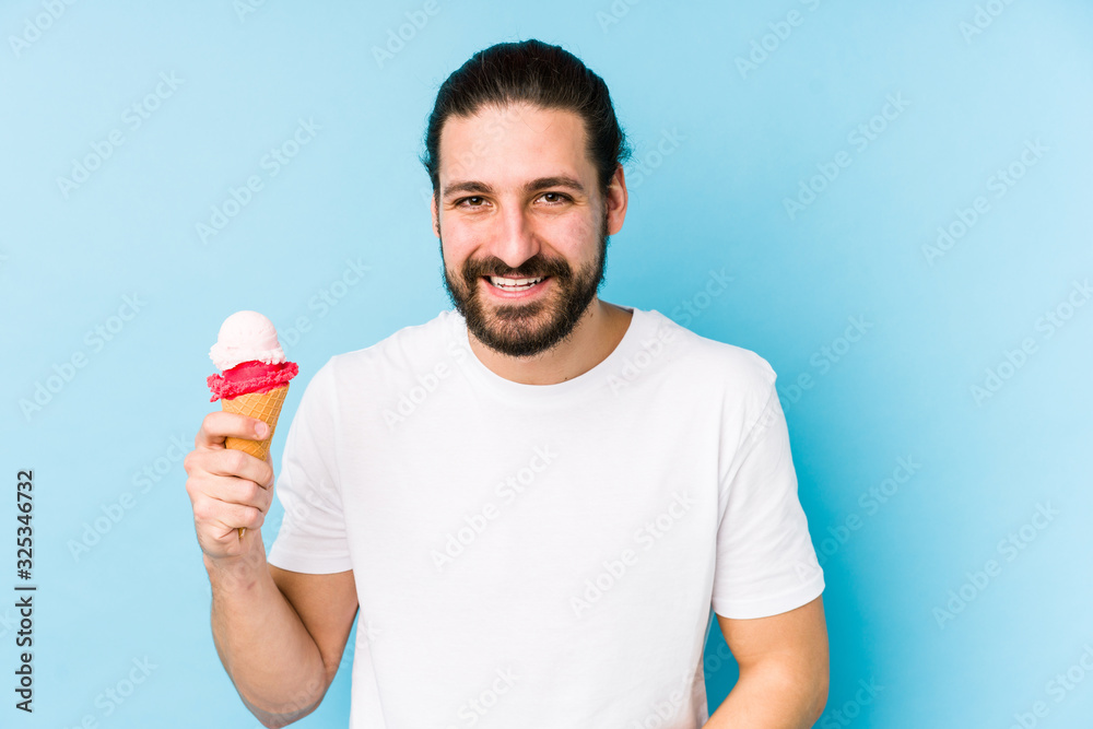 Young caucasian man eating an ice cream isolated laughing and having fun. Young caucasian man eating an ice cream isolated laughing and having fun.
