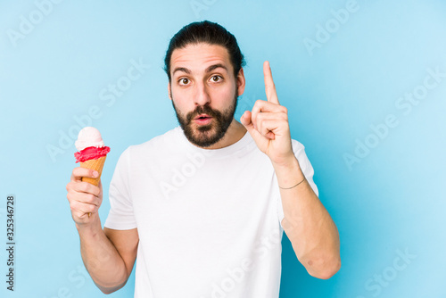 Young caucasian man eating an ice cream isolated having an idea, inspiration concept.