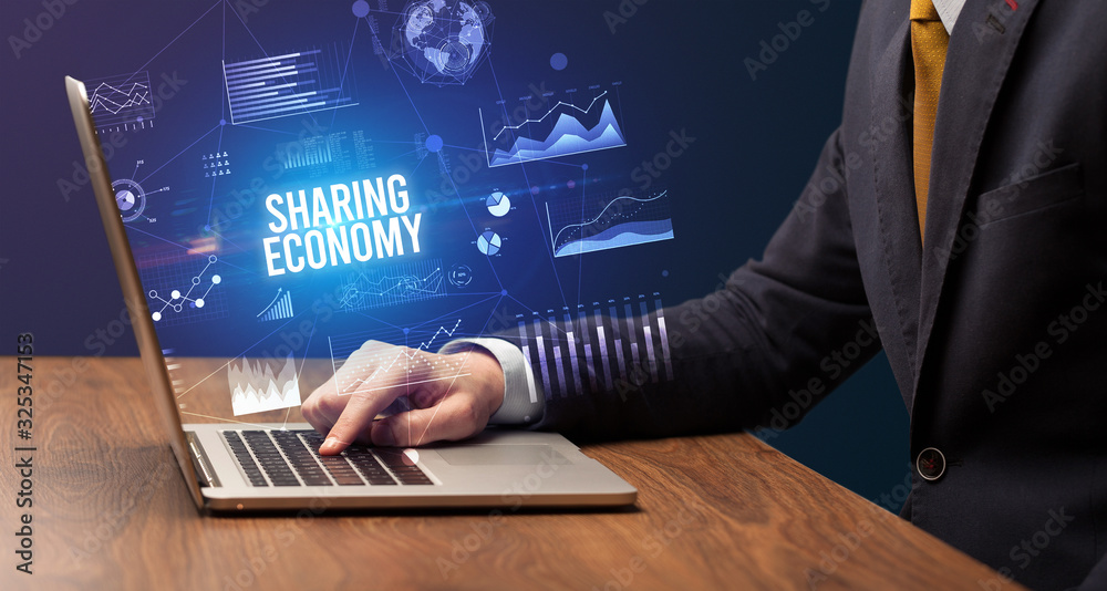 Businessman working on laptop with SHARING ECONOMY inscription, new business concept Businessman working on laptop with SHARING ECONOMY inscription, new business concept