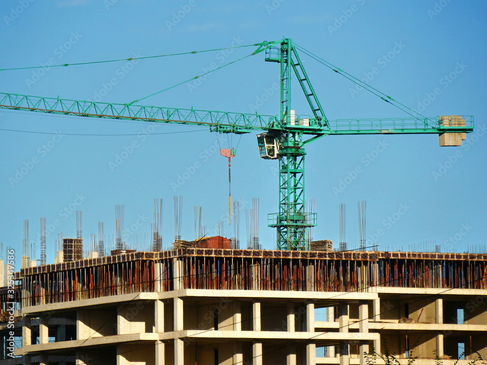 Construction crane near the building under construction. Concrete building under construction. Construction site.