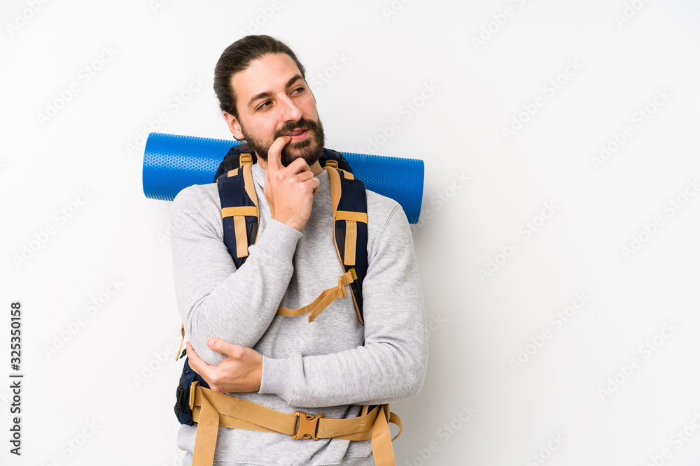 Young backpacker man isolated on a white background relaxed thinking about something looking at a copy space. Young backpacker man isolated on a white background relaxed thinking about something looking at a copy space.