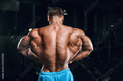 Bodybuilder strong man pumping up biceps muscles