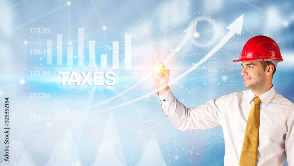 Young businessman with helmet drawing TAXES inscription, modern business technology concept Young businessman with helmet drawing TAXES inscription, modern business technology concept
