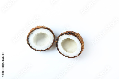 Top view shot of coconuts cracked on halves on paper textured background with a lot of copy space for text. Bacground with raw fruit of tropical palm. Flat lay.