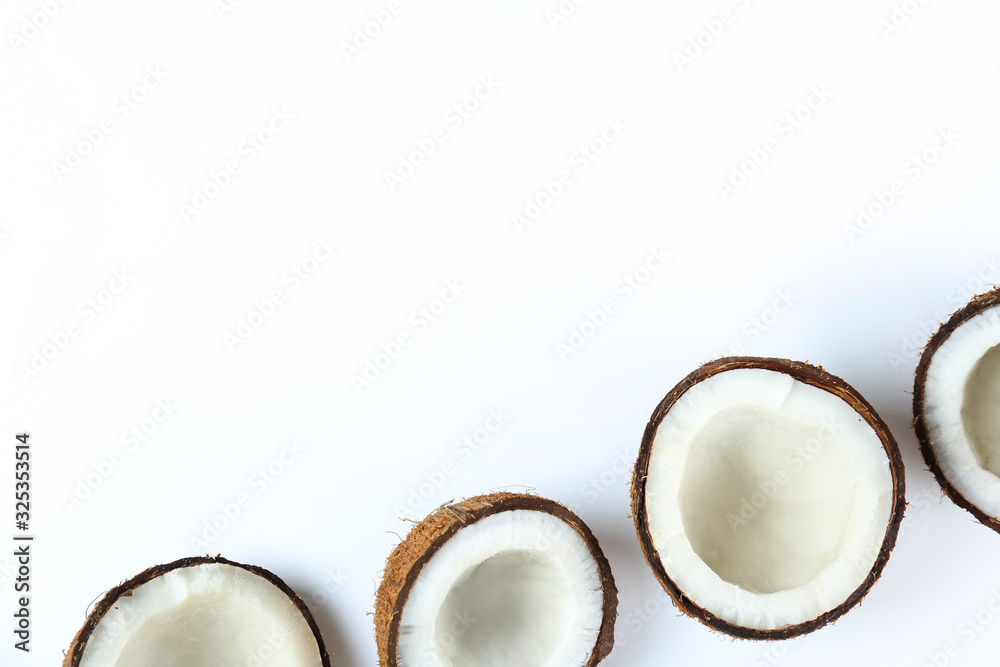 Top view shot of coconuts cracked on halves on paper textured background with a lot of copy space for text. Bacground with raw fruit of tropical palm. Flat lay. Top view shot of coconuts cracked on halves on paper textured background with a lot of copy space for text. Bacground with raw fruit of tropical palm. Flat lay.