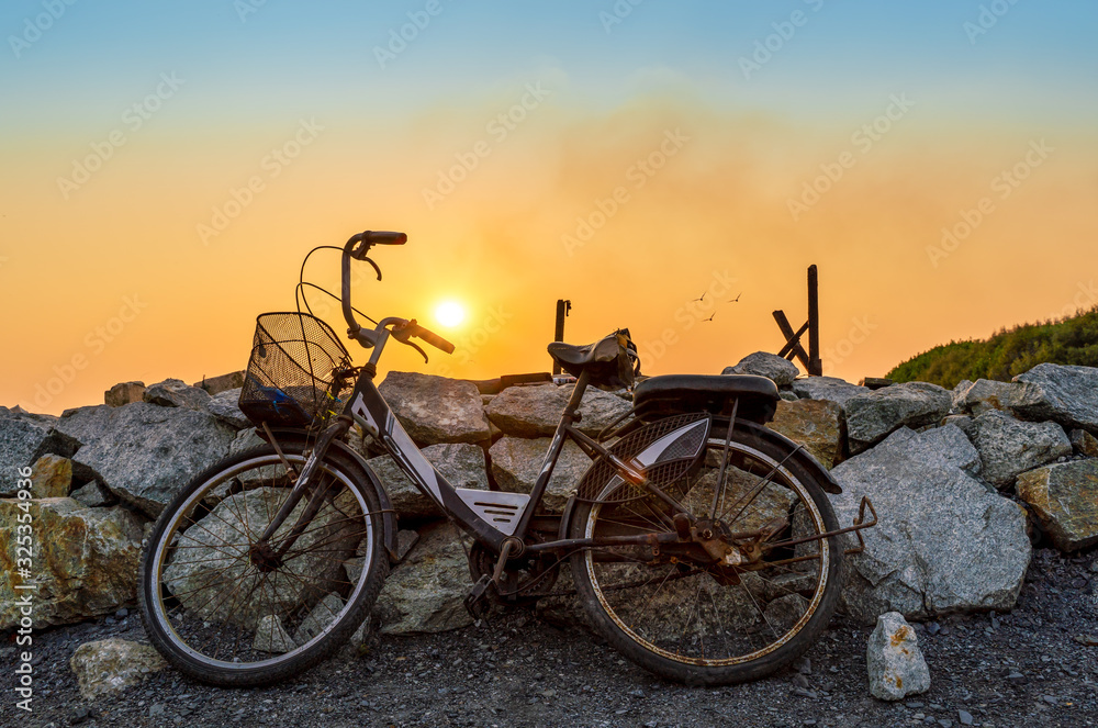 Fototapeta premium old rusty bike with beautiful sun at background