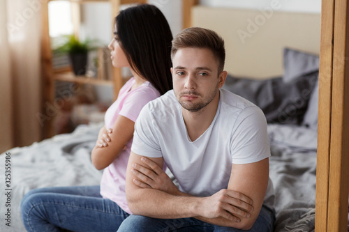 Offended Couple Sitting On Different Sides Of Bed At Home