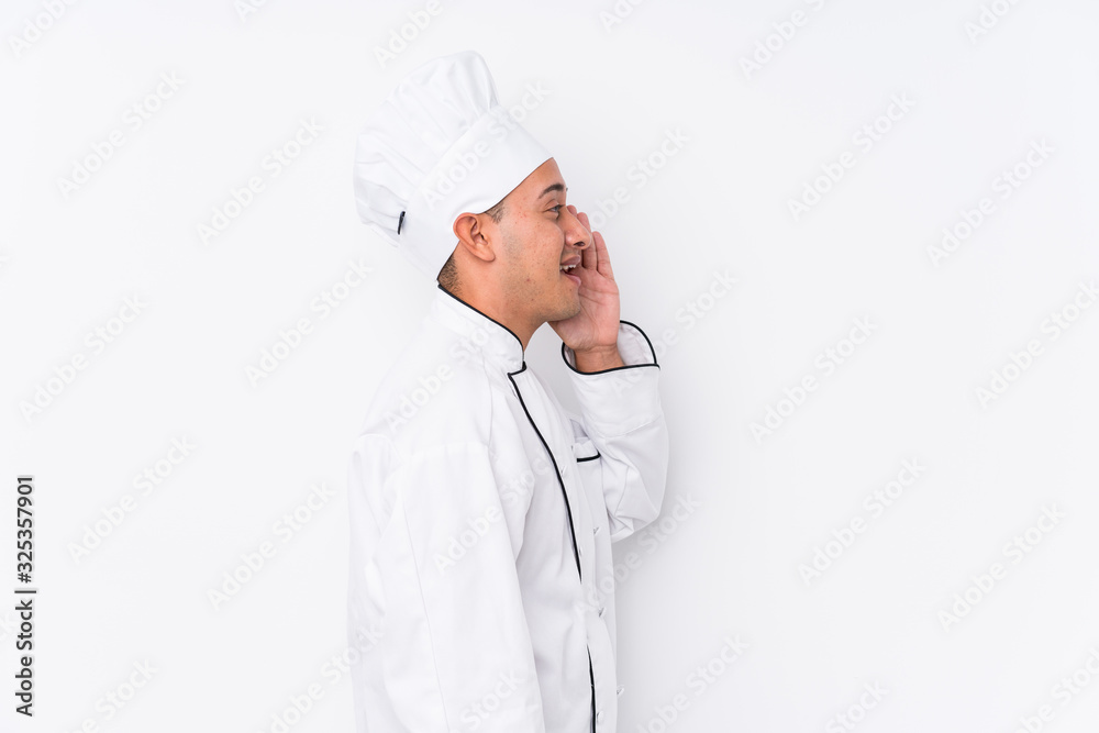 Young latin chef man isolated shouting and holding palm near opened mouth. Young latin chef man isolated shouting and holding palm near opened mouth.