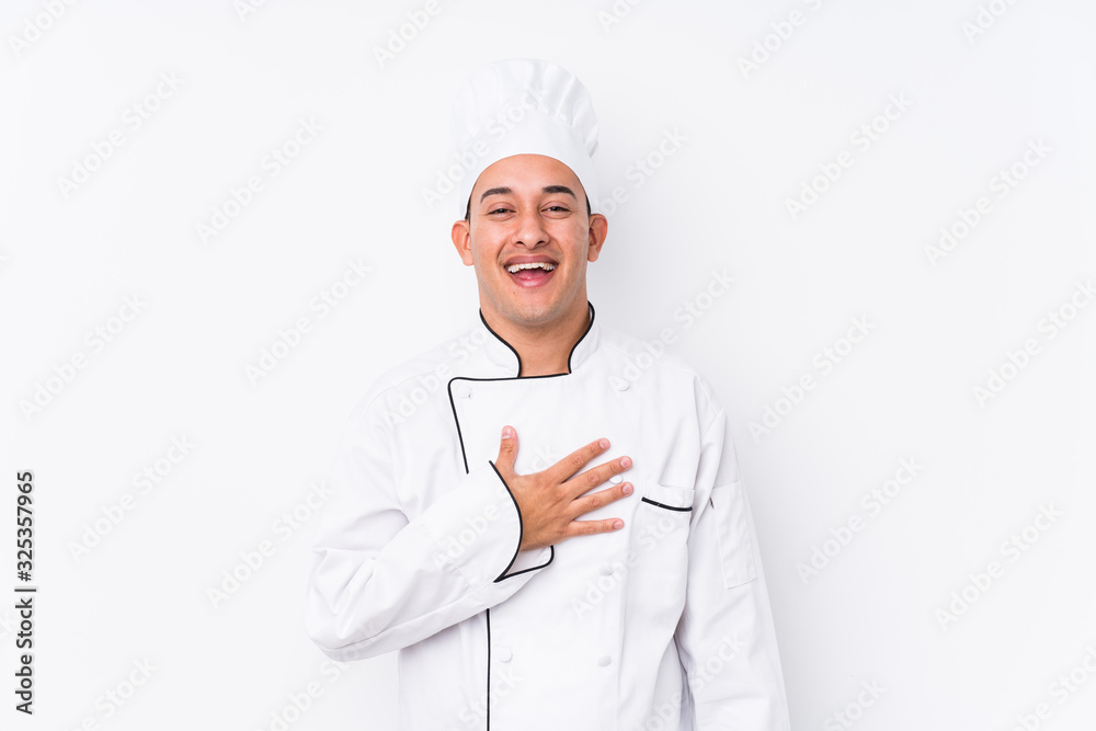 Young latin chef man isolated laughs out loudly keeping hand on chest. Young latin chef man isolated laughs out loudly keeping hand on chest.