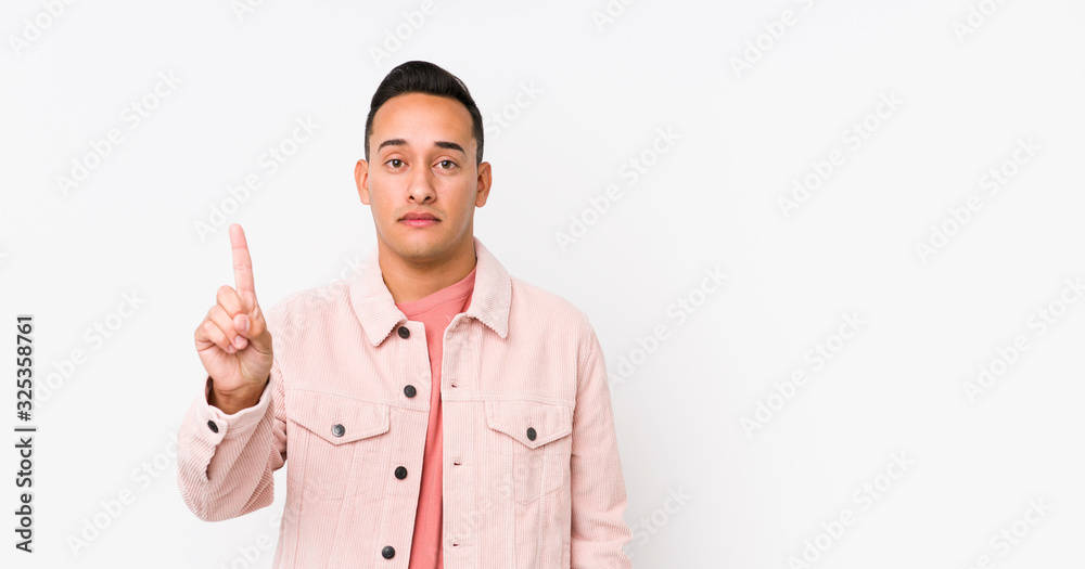 Young latin man posing isolated showing number one with finger. Young latin man posing isolated showing number one with finger.