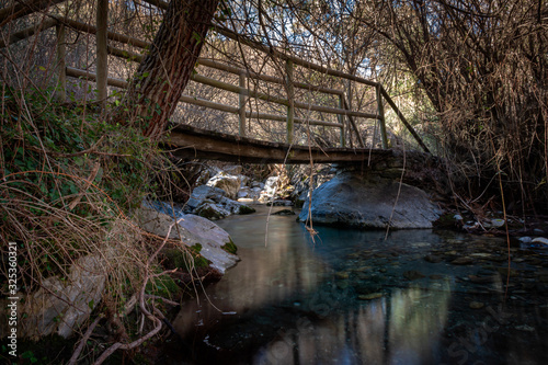 Wooden bridge between trees on the Dilar river. photo