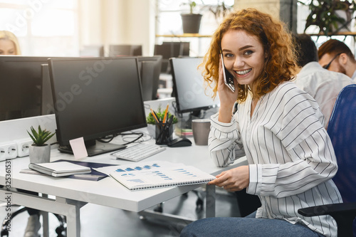 Positive young woman having business conversation by phone