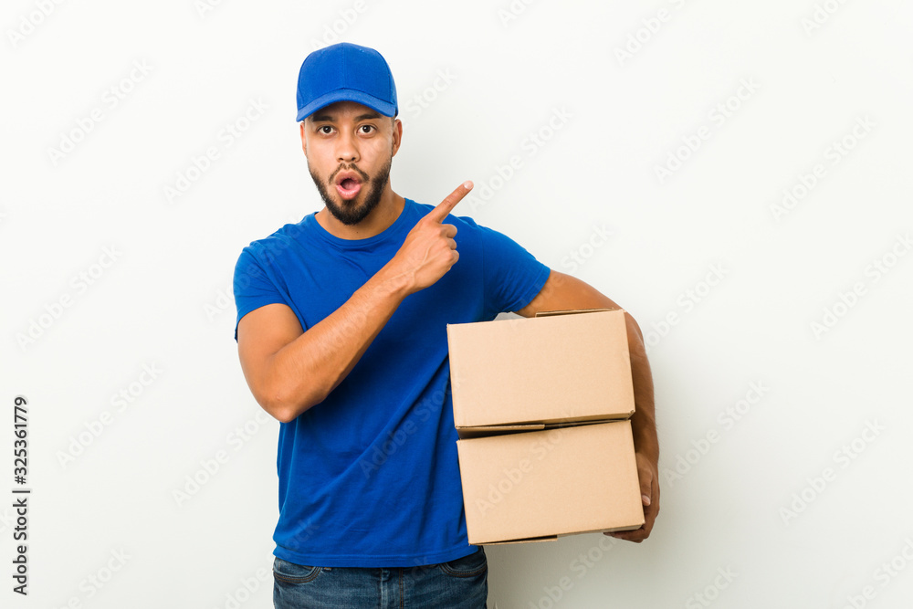 Young south-asian delivery man pointing to the side Young south-asian delivery man pointing to the side