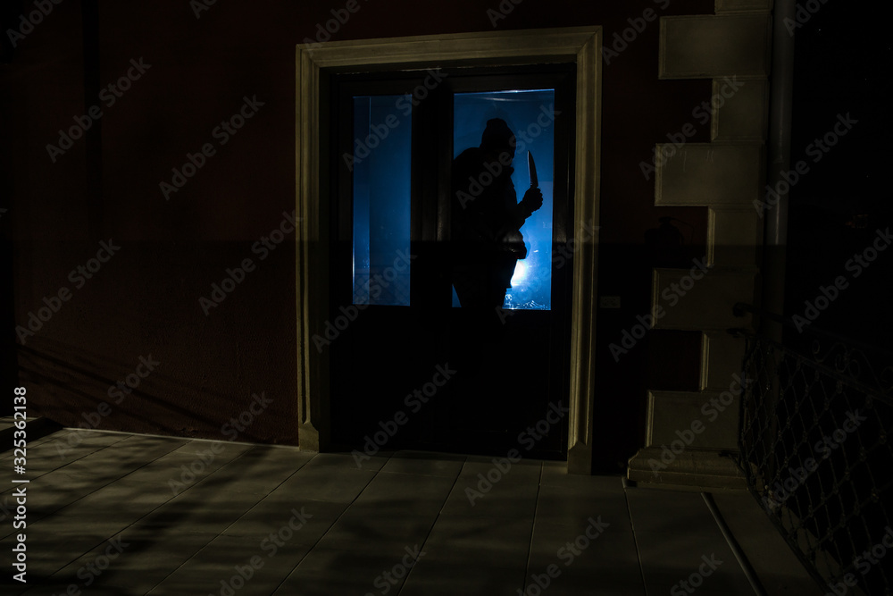 The silhouette of a human in front of a window at night. Scary scene halloween concept of blurred silhouette of maniac.